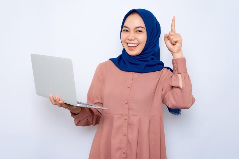 Smiling,Young,Asian,Muslim,Woman,In,Pink,Shirt,Holding,Laptop,