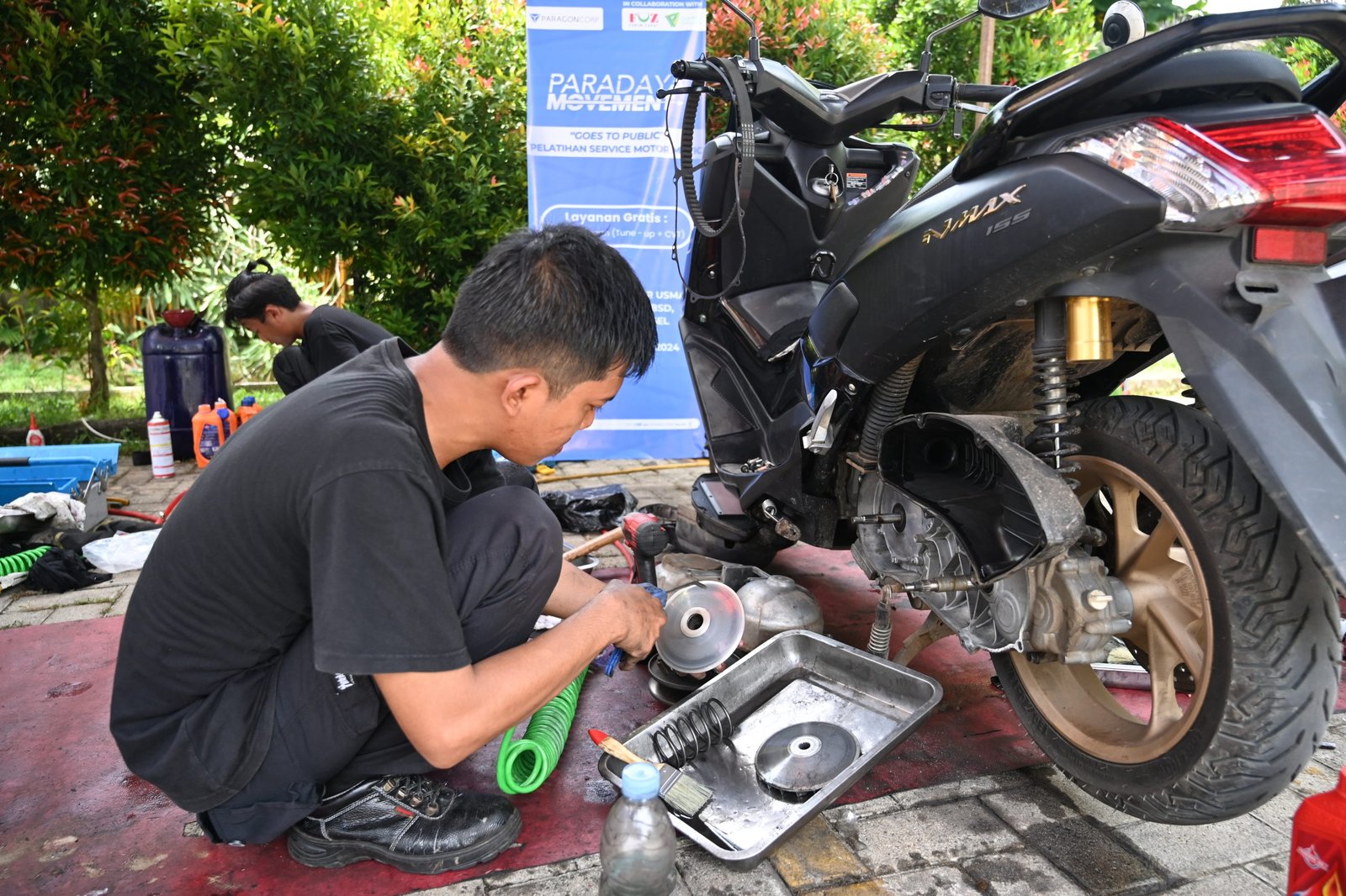 Dibimbing oleh Instruktur, peserta pelatihan Paradaya Movement melakukan praktek langsung layanan service motor gratis dalam ‘Goes to Public’ di wilayah Serpong, Tangerang Selatan, pada Selasa, (26/11/2024).