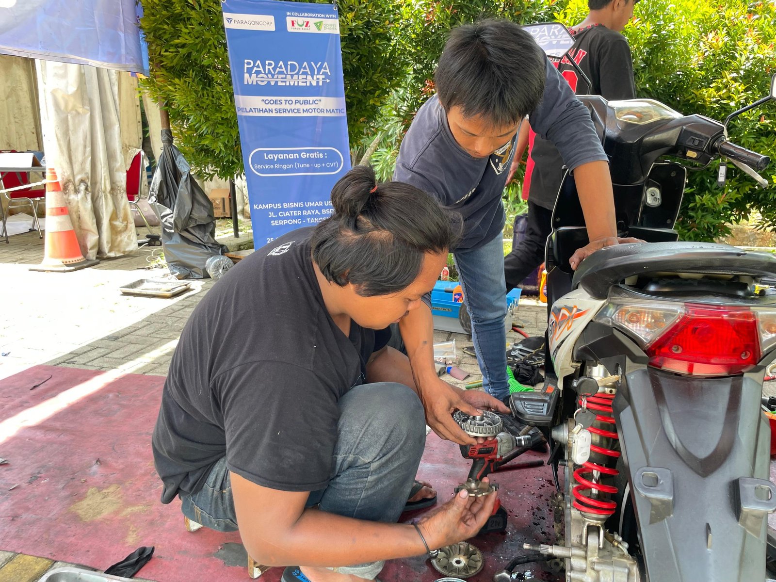 Dibimbing oleh Instruktur, peserta pelatihan Paradaya Movement melakukan praktek langsung layanan service motor gratis dalam ‘Goes to Public’ di wilayah Serpong, Tangerang Selatan, pada Selasa, (26/11/2024).