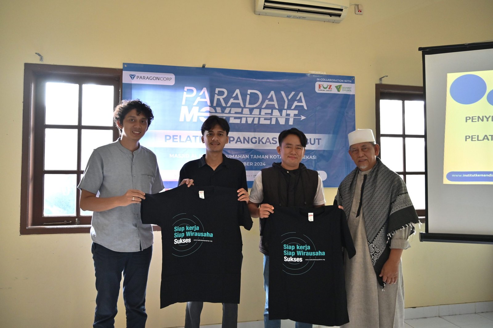 Simbolis penyerahan kaos sebagai penanda dimulainya pelatihan oleh Owner Sekolah Barber indonesia, Sendhy Desmijaya dan Ketua DKM Masjid Al Huda Bekasi, kepada perwakilan peserta pangkas rambut. Bekasi, Selasa (10/12/2024).
