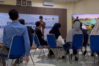 Instruktur Setiawan Chogah memberikan materi literasi finansial Merawat Kebun Rezeki kepada peserta pelatihan Barber, Menjahit, dan Bright Migrant Worker di ruang kelas Institut Kemandirian, Karawaci, Tangerang, dengan presentasi ilustrasi kebun rezeki ditampilkan di layar.
