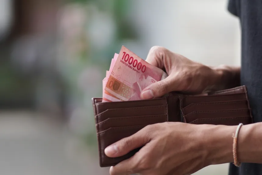 Seseorang memegang dompet berisi uang rupiah sebagai ilustrasi pengelolaan keuangan dan konsep Lega Finansial.