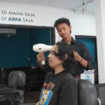Febri Nur Hidayanto, alumni Pelatihan Barber Institut Kemandirian, sedang melayani pelanggan sebagai barberman di Arfa Barber Gerai Bantul.