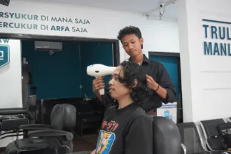 Febri Nur Hidayanto, alumni Pelatihan Barber Institut Kemandirian, sedang melayani pelanggan sebagai barberman di Arfa Barber Gerai Bantul.