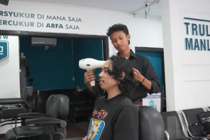 Febri Nur Hidayanto, alumni Pelatihan Barber Institut Kemandirian, sedang melayani pelanggan sebagai barberman di Arfa Barber Gerai Bantul.