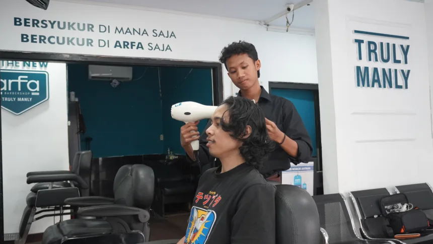Febri Nur Hidayanto, alumni Pelatihan Barber Institut Kemandirian, sedang melayani pelanggan sebagai barberman di Arfa Barber Gerai Bantul.